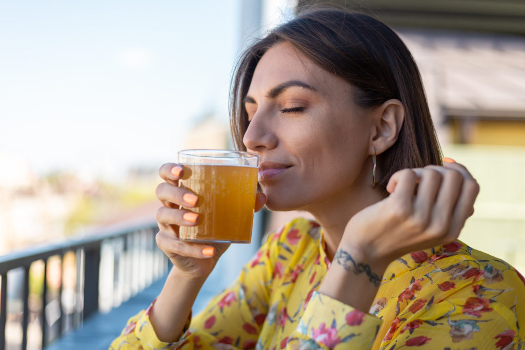 woman-in-dress-in-summer-cafe-enjoying-cool-kombuc-2022-01-19-00-07-59-utc-1024x683